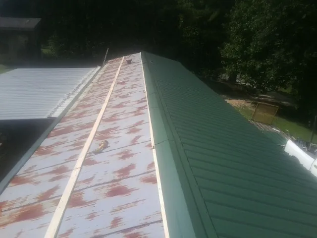Old rusted panels beside newly installed green metal roofing — Wind Damage Roof Repair by Roofing Brothers in Blue Springs