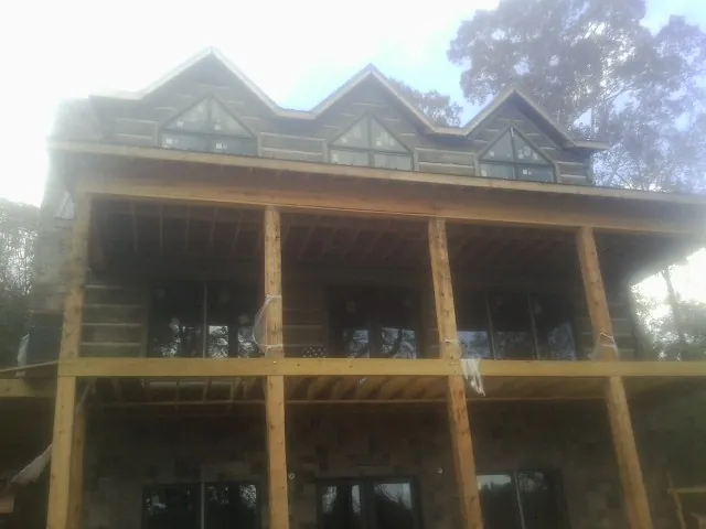 Dormers and porch framing on a large log home under construction — Roof Coating work by our crew in Blue Springs