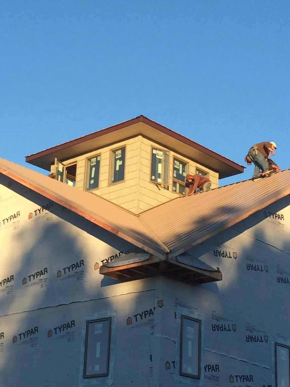 Roofers working around a rooftop cupola on a new metal roof at sunset — Roof Waterproofing in Blue Springs by Roofing Brothers